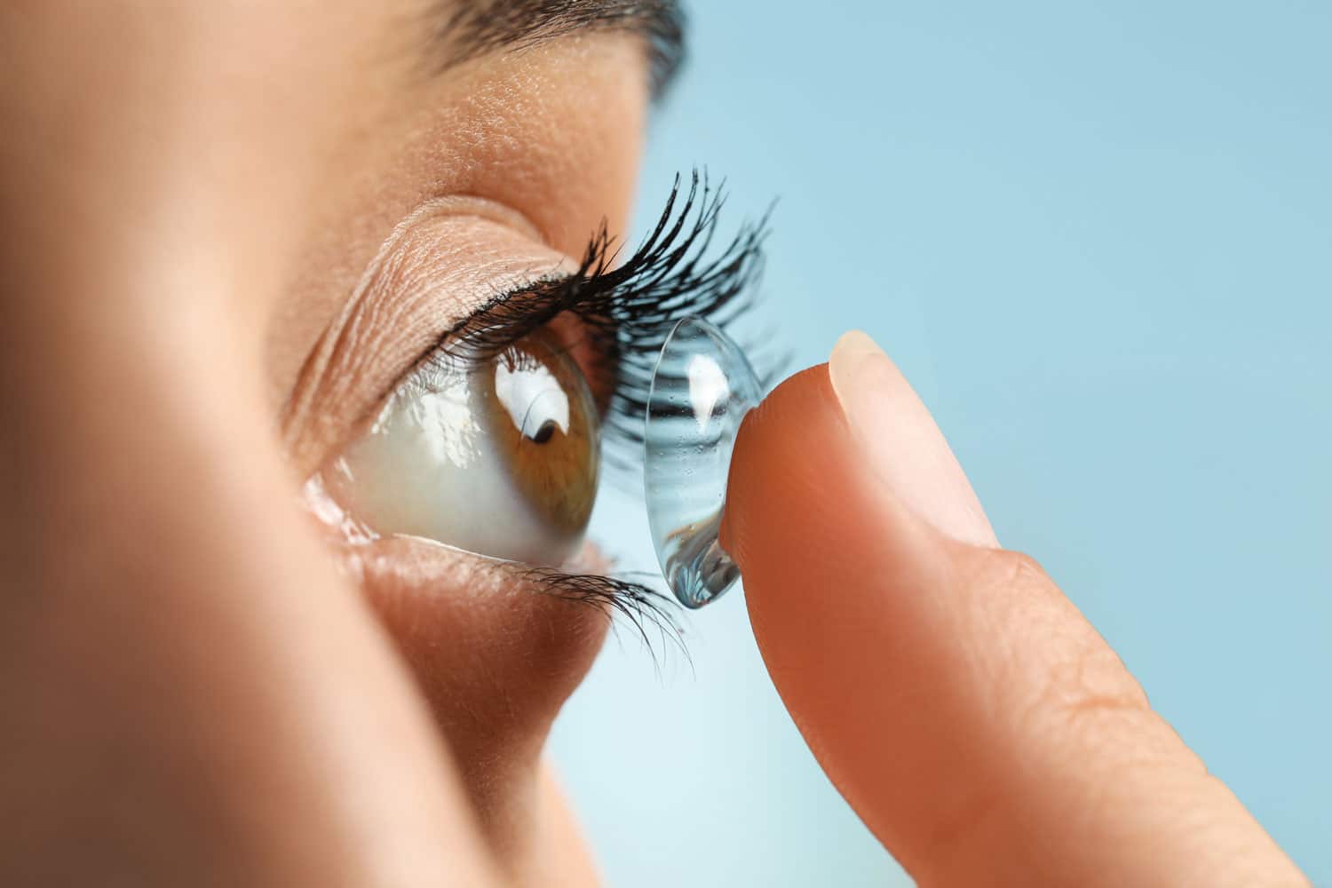 Close up of a woman putting a contact lens in her eye